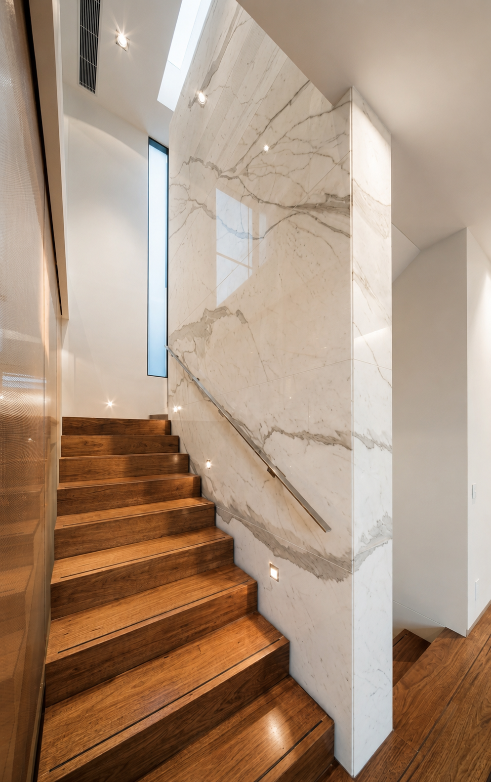 Walnut staircase with LED step lighting and marble wall